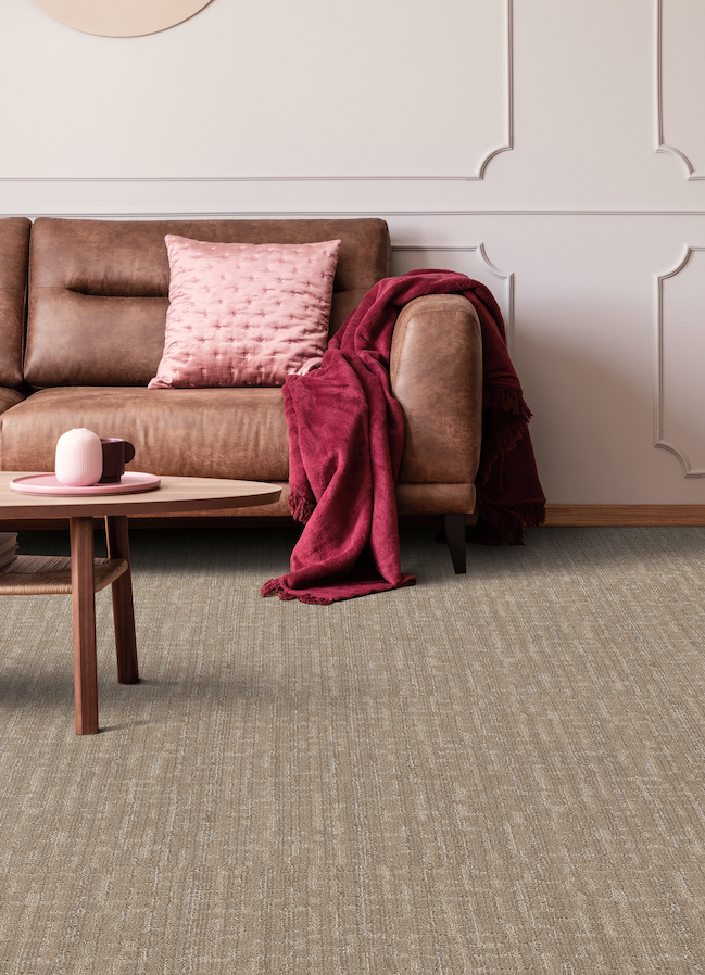 textured brown carpet in a stylish living room with a brown leather couch and pink accents