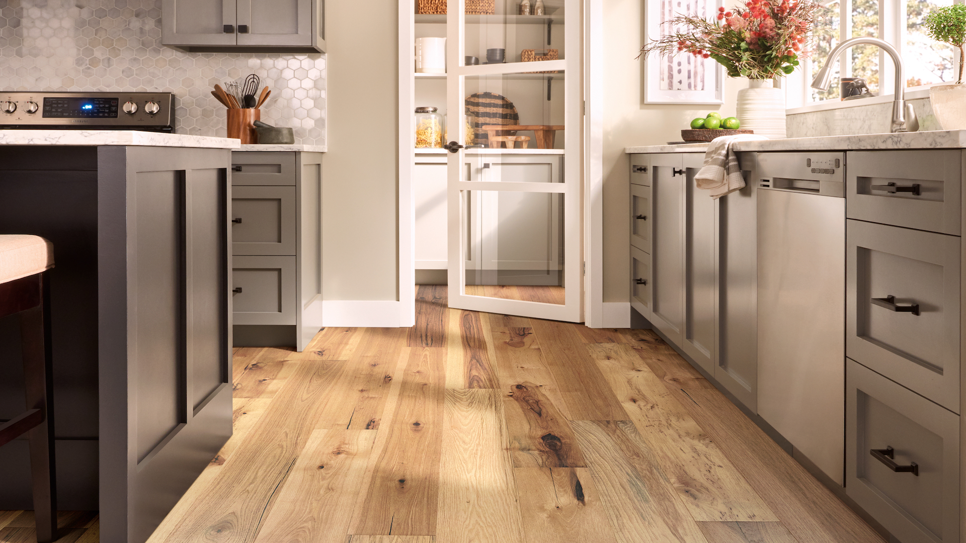 light toned hardwood flooring in a stylish kitchen with grey cabinets and island
